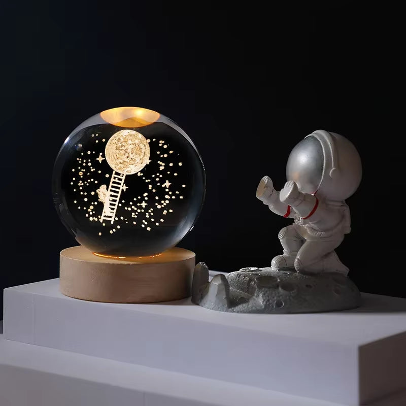 Decorative sphere with astronaut and ladder design next to a small astronaut figure on a dark background