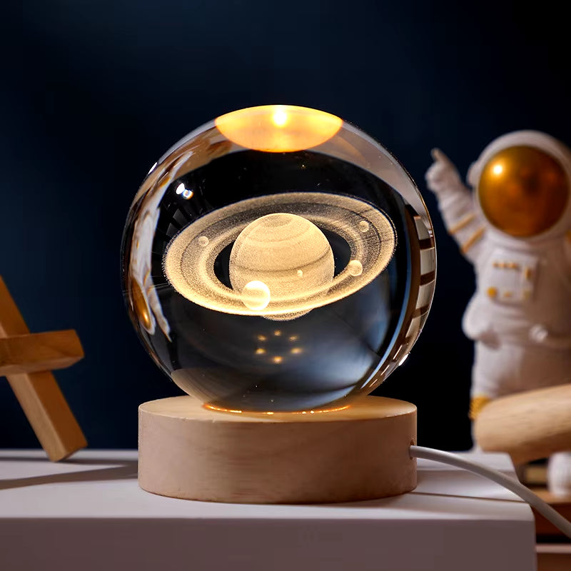 Glass orb with Saturn model on a wooden base, with an astronaut figure in the background.