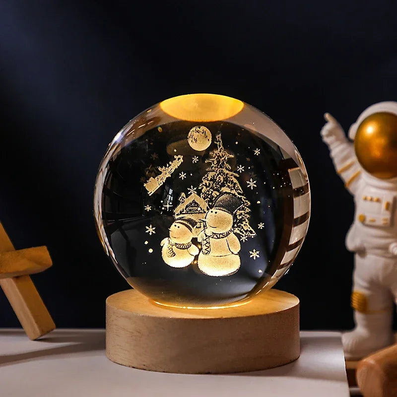 Decorative crystal ball with snowmen and a tree on a wooden base, with an astronaut figure in the background.