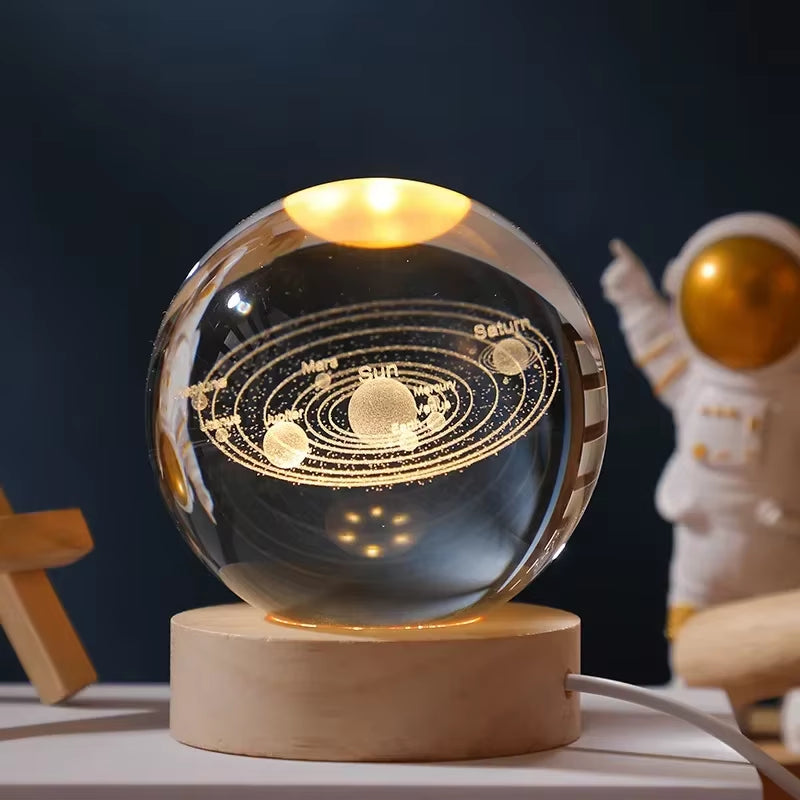 Crystal ball with solar system model on a wooden base, illuminated against a dark background.